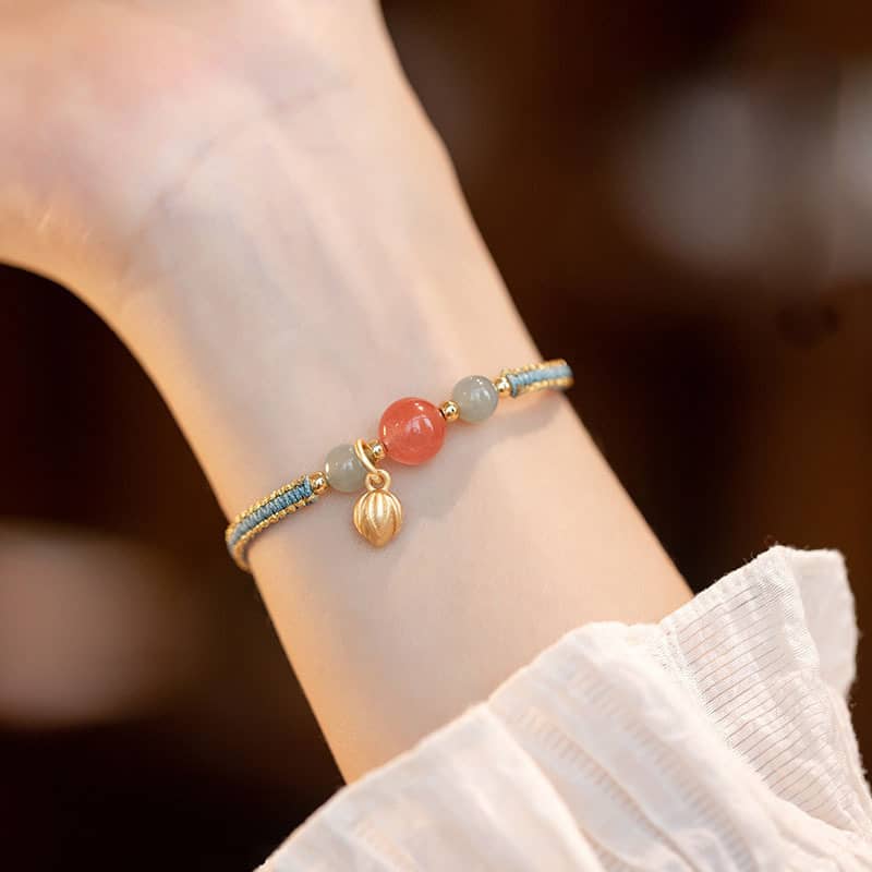 Red chalcedony lotus bracelet with decorative beads on a woven cord, perfect for mindful relaxation
