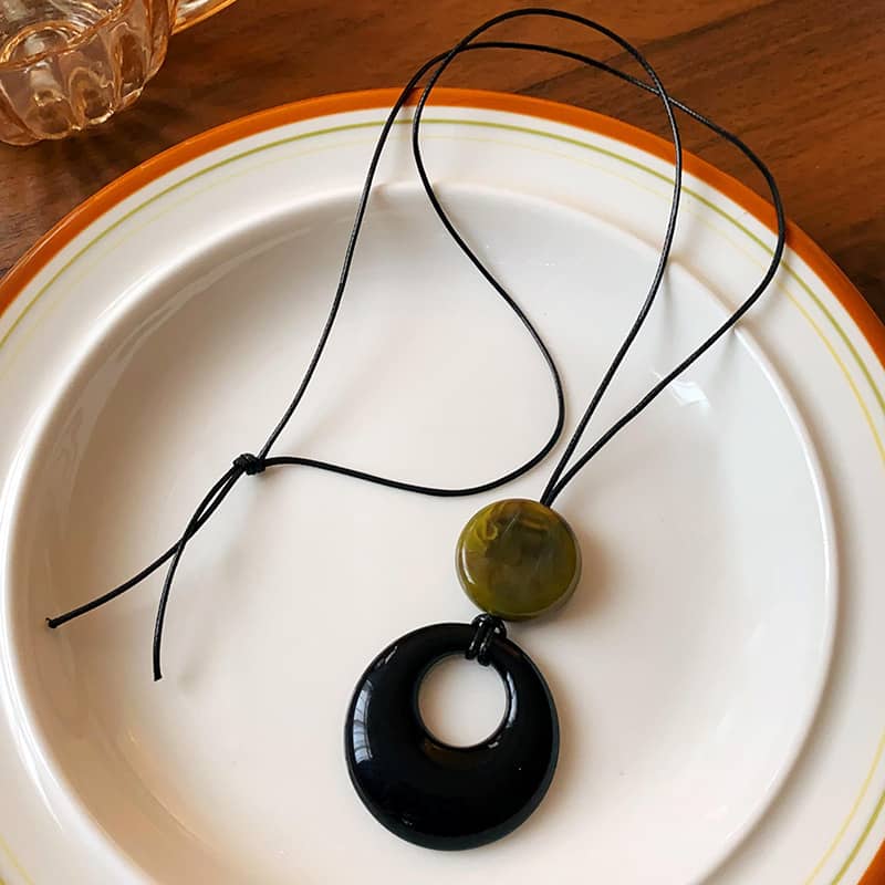 Angry resin pendant necklace for mindfulness with black and green circular pendants on a cord