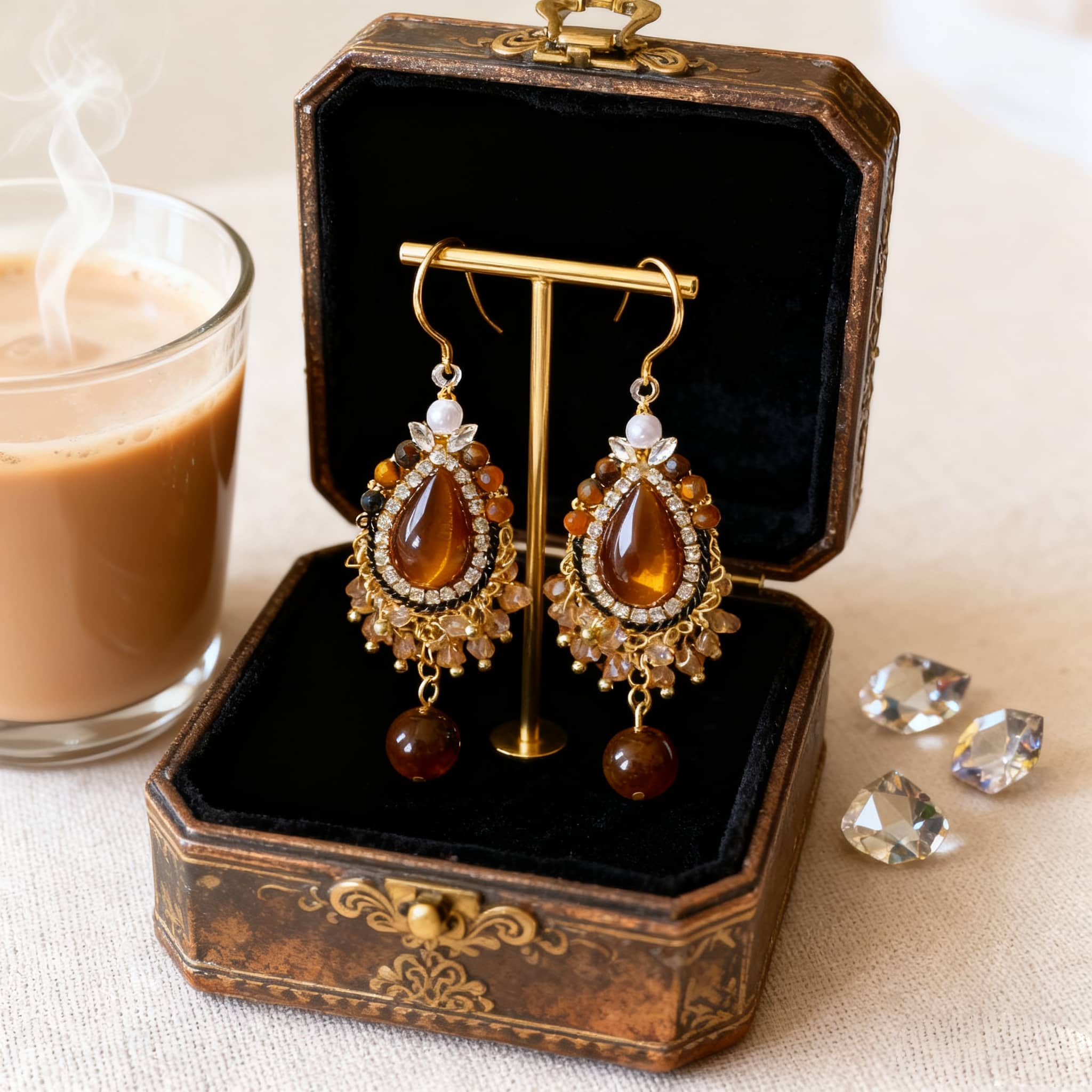 Elegant tiger's eye anxiety relief earrings displayed in a vintage jewelry box beside a cup of coffee