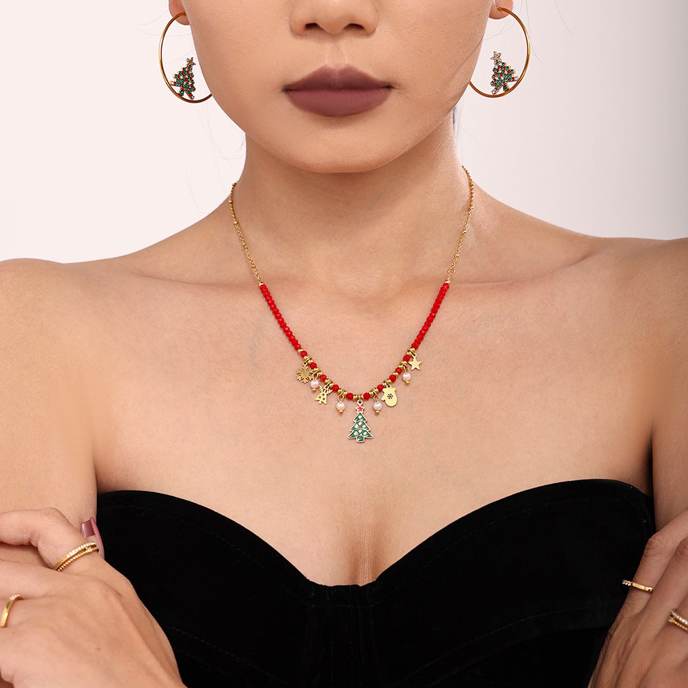 Gold Christmas tree necklace with red beads and holiday charms worn by model with matching earrings
