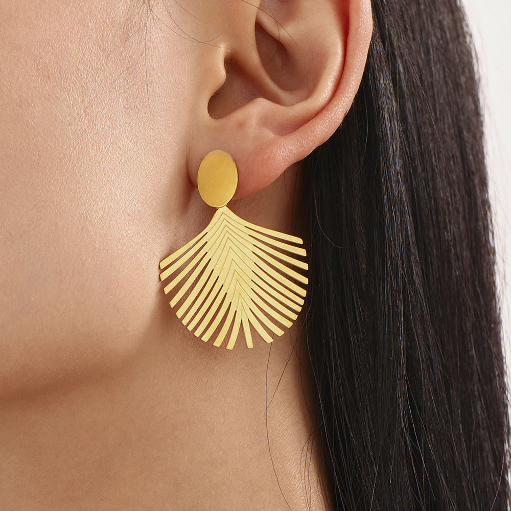 Close-up of gold palm leaf earrings worn on ear showcasing elegant design and smooth finish