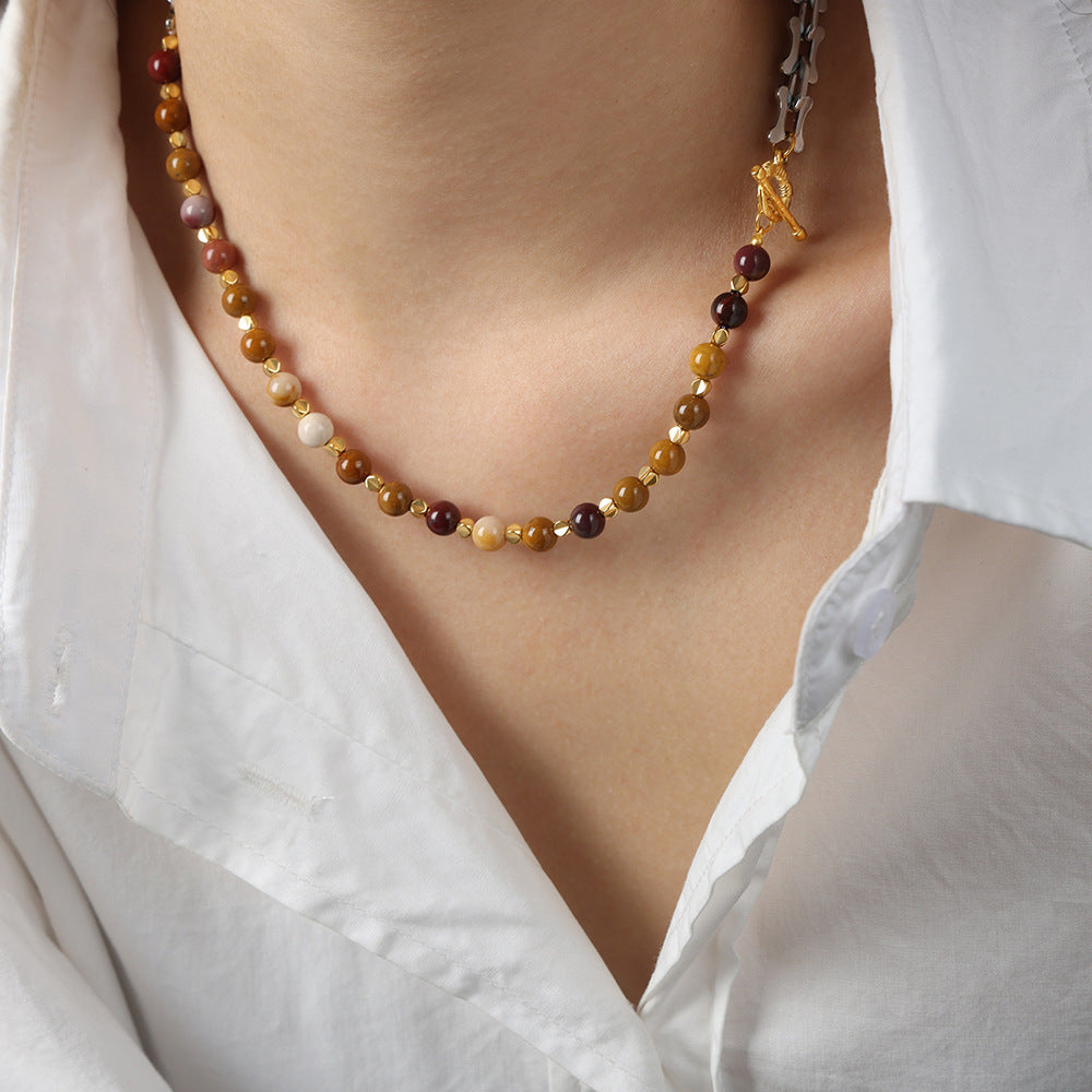 Mixed metal bead choker necklace with brown and gold beads worn with a white shirt