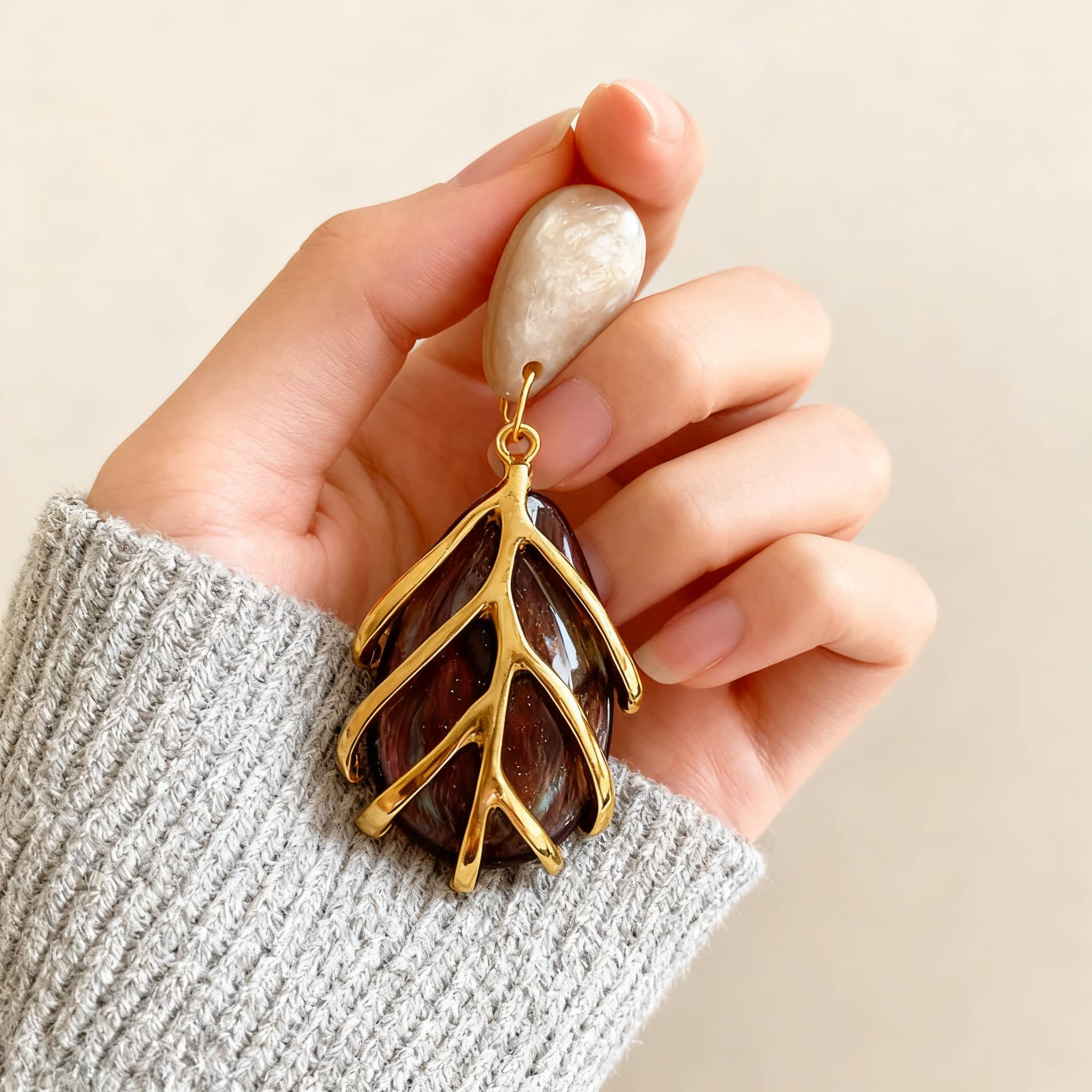 Hand holding vintage metal cage statement earrings with a unique natural design and earthy tones