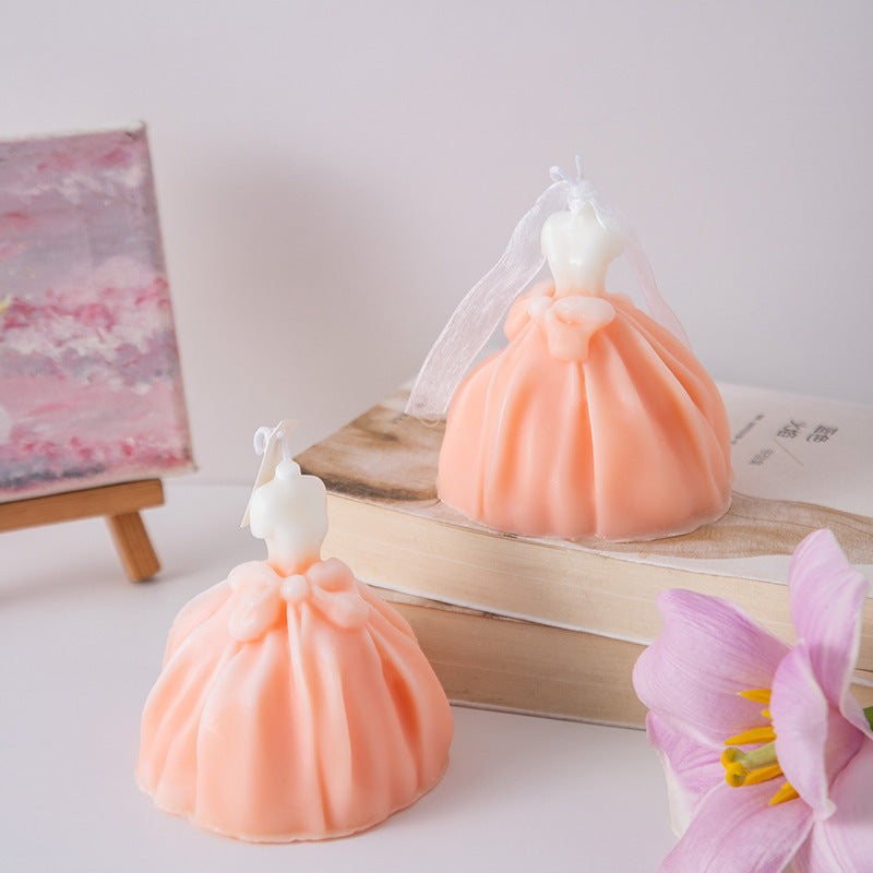 Peach colored wedding dress candle shaped like a bride with veil on a wooden surface