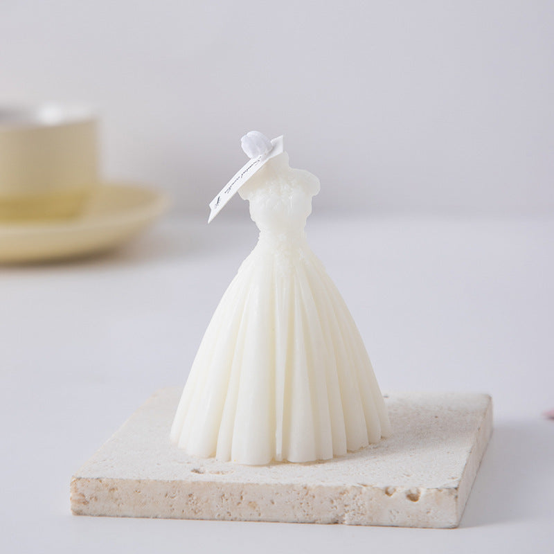 White wedding dress candle shaped like a bridal gown on a textured square stone base
