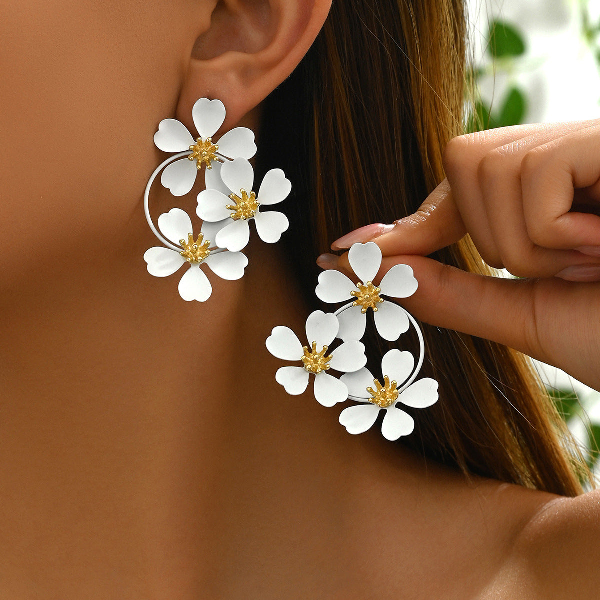 Close-up of white sunflower earrings worn on ear and held by hand showcasing floral design