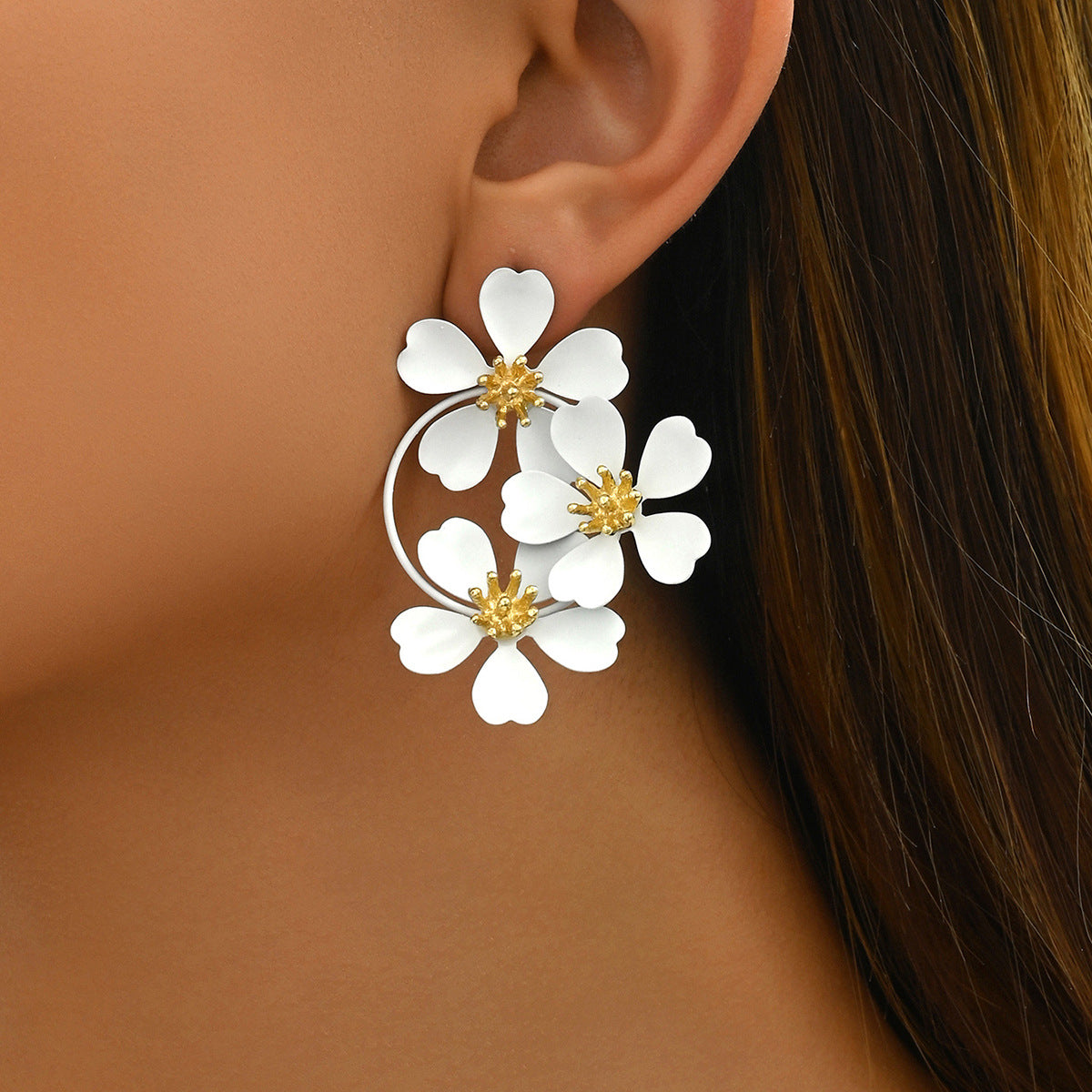 Close-up of white sunflower earrings with gold centers worn on ear for elegant style