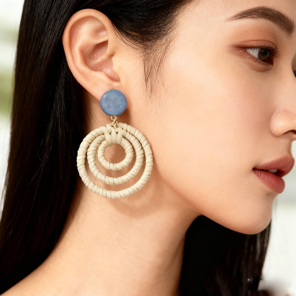 Woven bamboo statement earrings with a circular design and blue accent, perfect for stylish outfits